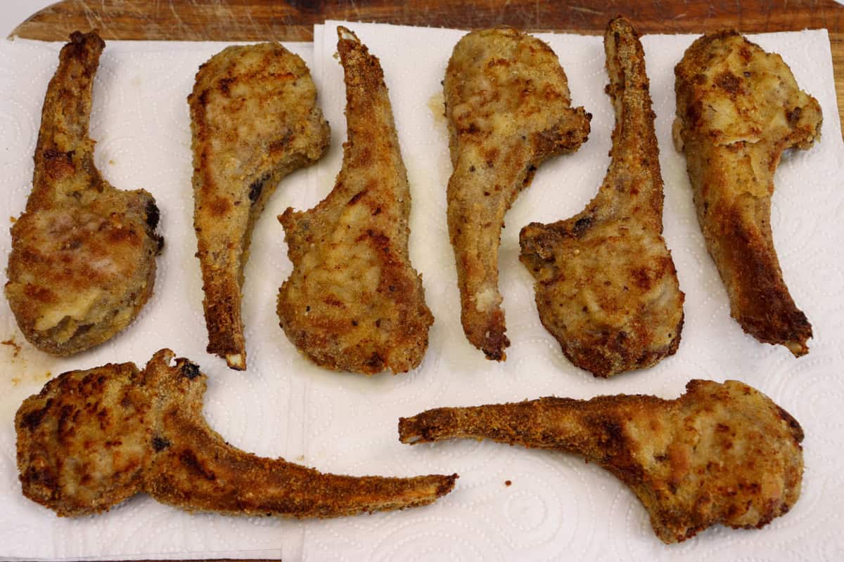 After cooking, the crumbed lamb cutlets are rested on paper towel