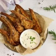 Crumbed lamb cutlets served in a bowl with a small bowl of sauce