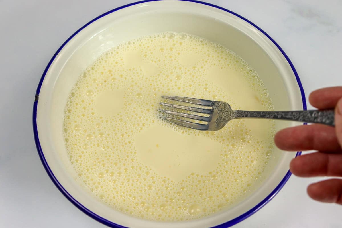 Milk and egg is whisked in a dish with a fork