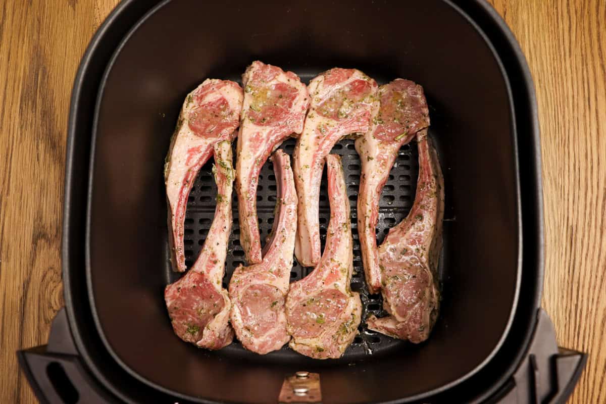 The lamb cutlets are laid in the air fryer basket in 2 rows of 4 in a single layer