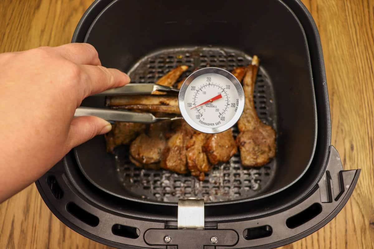 Using a meat thermometer to check the internal temperature of the lamb cutlets after cooking