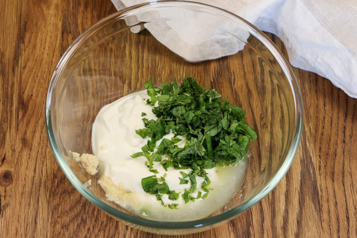 Yogurt, mint, garlic and lemon juice are added to a mixing bowl