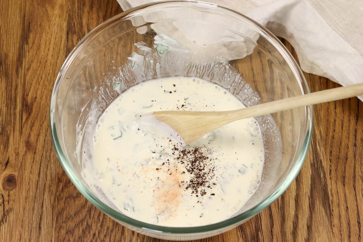 Salt and pepper is added to season the yogurt and mint sauce