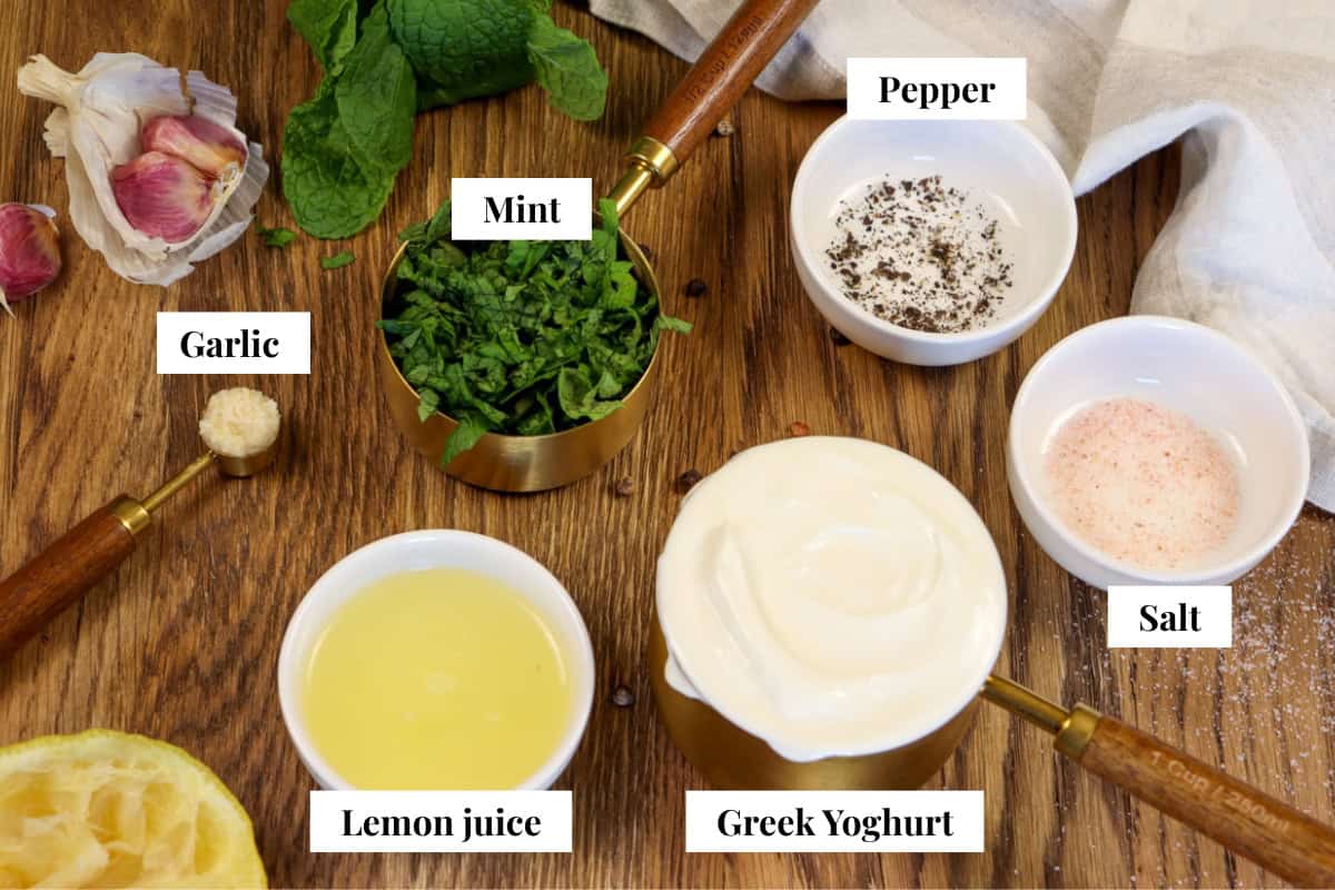 Ingredients for mint and yogurt sauce for lamb including garlic, mint, pepper, salt, greek yogurt and lemon juice